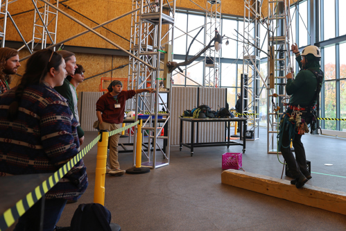 Students observe a Davey trainer utilizing the indoor climber center structure