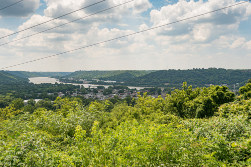 A view of many green trees, hills and a river in the distance. 