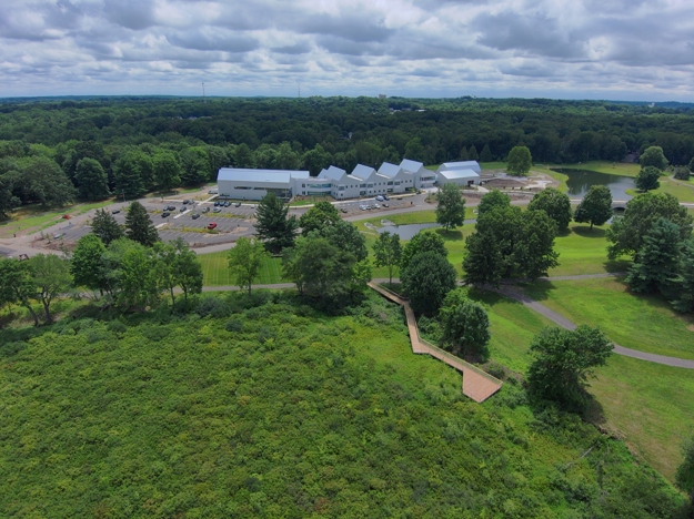 An aerial view of a large, green campus with a large, white facility on it.
