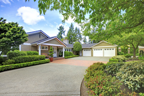 Green house with beautiful curb appeal. View of three car garage and driveway