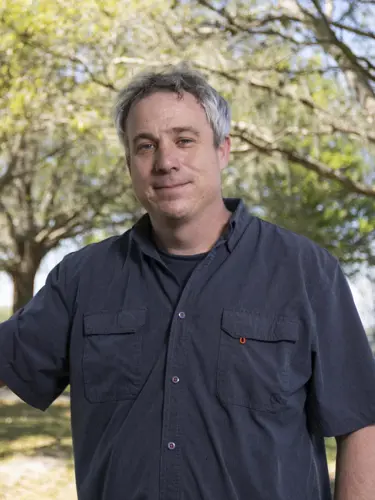 A person with a dark button up shirt smiling for a photo