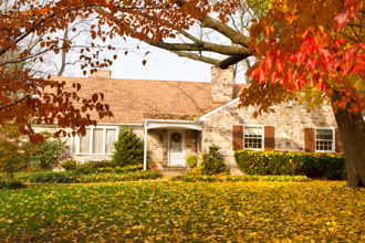 Single Family house with autumn leaves. Dogwood trees in the foreground, the yellow leaves are Norway Maple. Suburban Philadelphia, PA, USA.