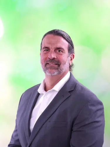 A headshot of a business professional in a gray suit jacket and white-collared shirt. 