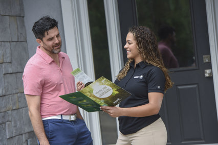 A woman showing a pamphlet to a man in a business conversation.