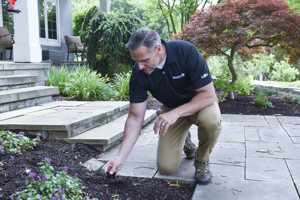 Arborists in a black davey polo handles mulch at a home