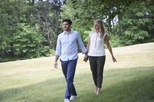 A man in a blue shirt and women in a white shirt walk through grass and trees